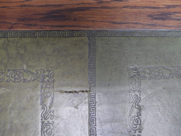 Nahaufnahme der originalen grünen Lederauflage mit geprägter Struktur. Die Aufnahme zeigt die hochwertige Verarbeitung sowie die charakteristische Oberfläche der historischen Schreibplatte.