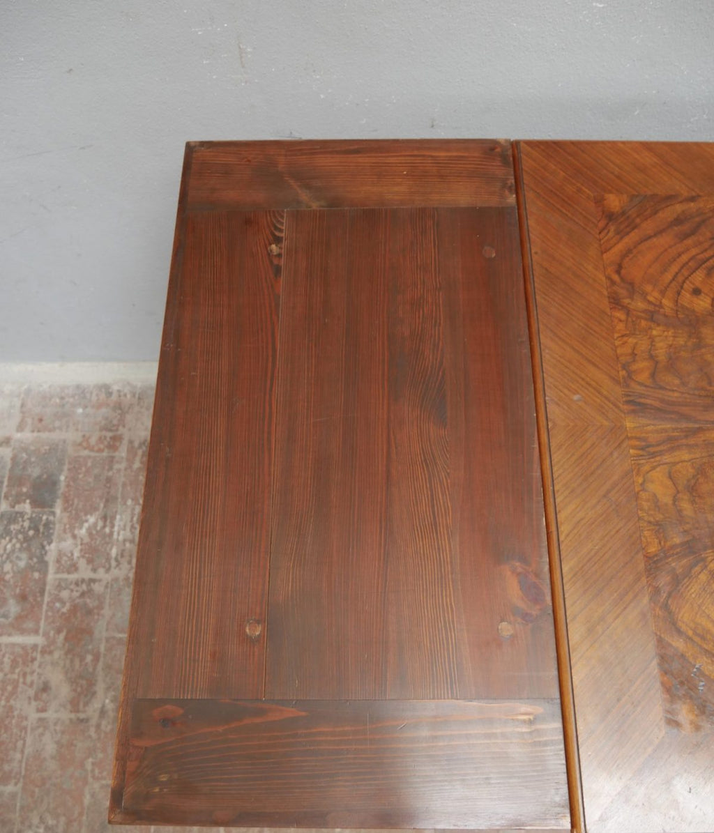 Detailaufnahme der furnierten Nussbaum-Tischplatte mit Spiegel, Fries und gespiegeltem Furnierbild.
