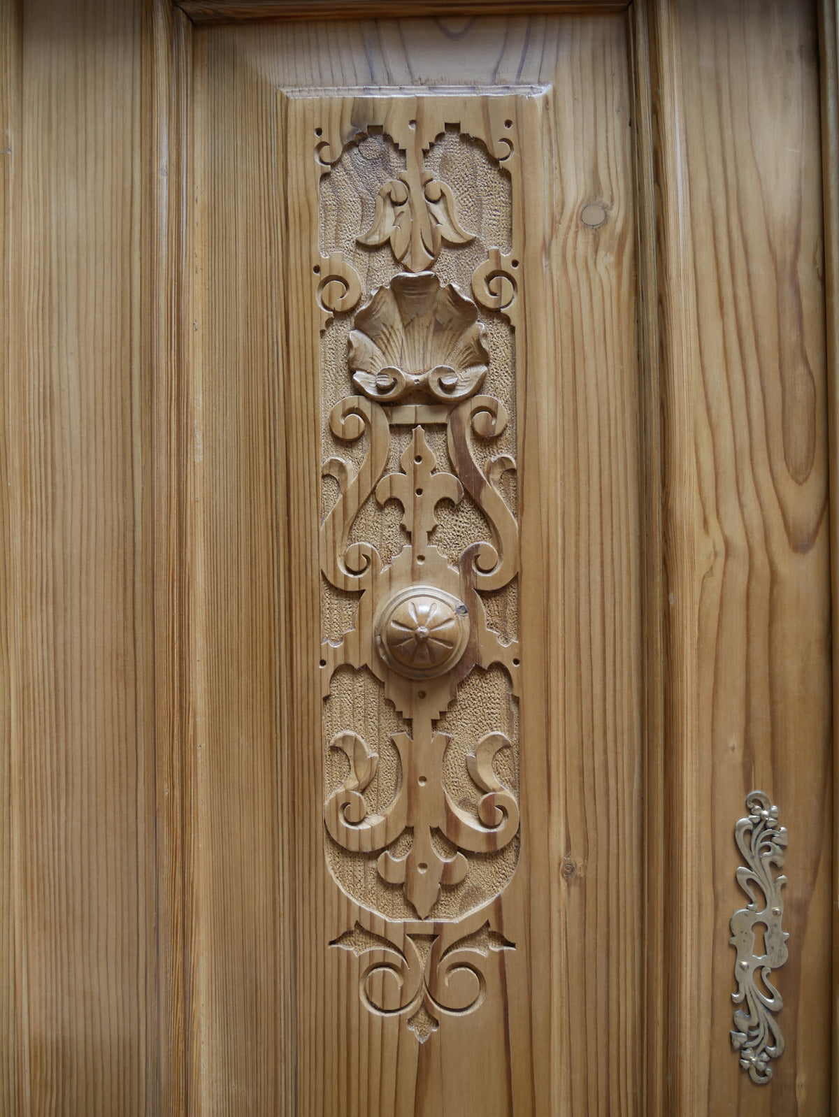 Detailaufnahme einer aufwendig geschnitzten Türfüllung des restaurierten Gründerzeit-Vertikos. Die dekorative Holzschnitzerei zeigt charakteristische florale und ornamentale Formen der Gründerzeit. Die warme Weichholzoberfläche, die plastische Schnitzarbeit und die handwerkliche Ausführung sind in dieser Nahaufnahme besonders gut erkennbar.