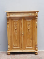 Frontale Detailansicht des restaurierten Gründerzeit-Vertikos aus Weichholz, um 1870. Beide Türen sind geschlossen und zeigen die geschnitzten, zeittypischen Gründerzeit-Ornamente. Zu sehen sind außerdem der profilierte obere Abschluss, dekorative seitliche Elemente, die originalen Beschläge und die charakteristische Sockelgestaltung des historischen Möbels.