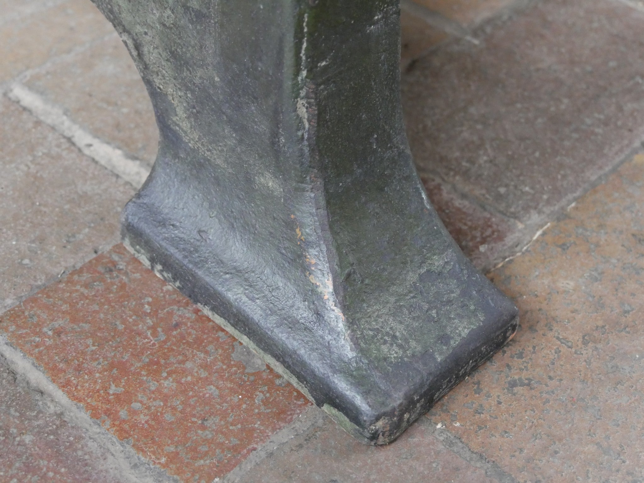 Detailansicht des massiven Standfußes aus Gusseisen. Sichtbar sind die kräftige Materialstärke, die originale Farboberfläche sowie altersbedingte Gebrauchsspuren des historischen Industriegestells.
