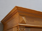 Detail der massiven Kranzleiste mit mehrfach profilierten Gesimsen und dekorativen Holzornamenten. Die Aufnahme zeigt die hochwertige handwerkliche Ausführung des oberen Abschlusses.