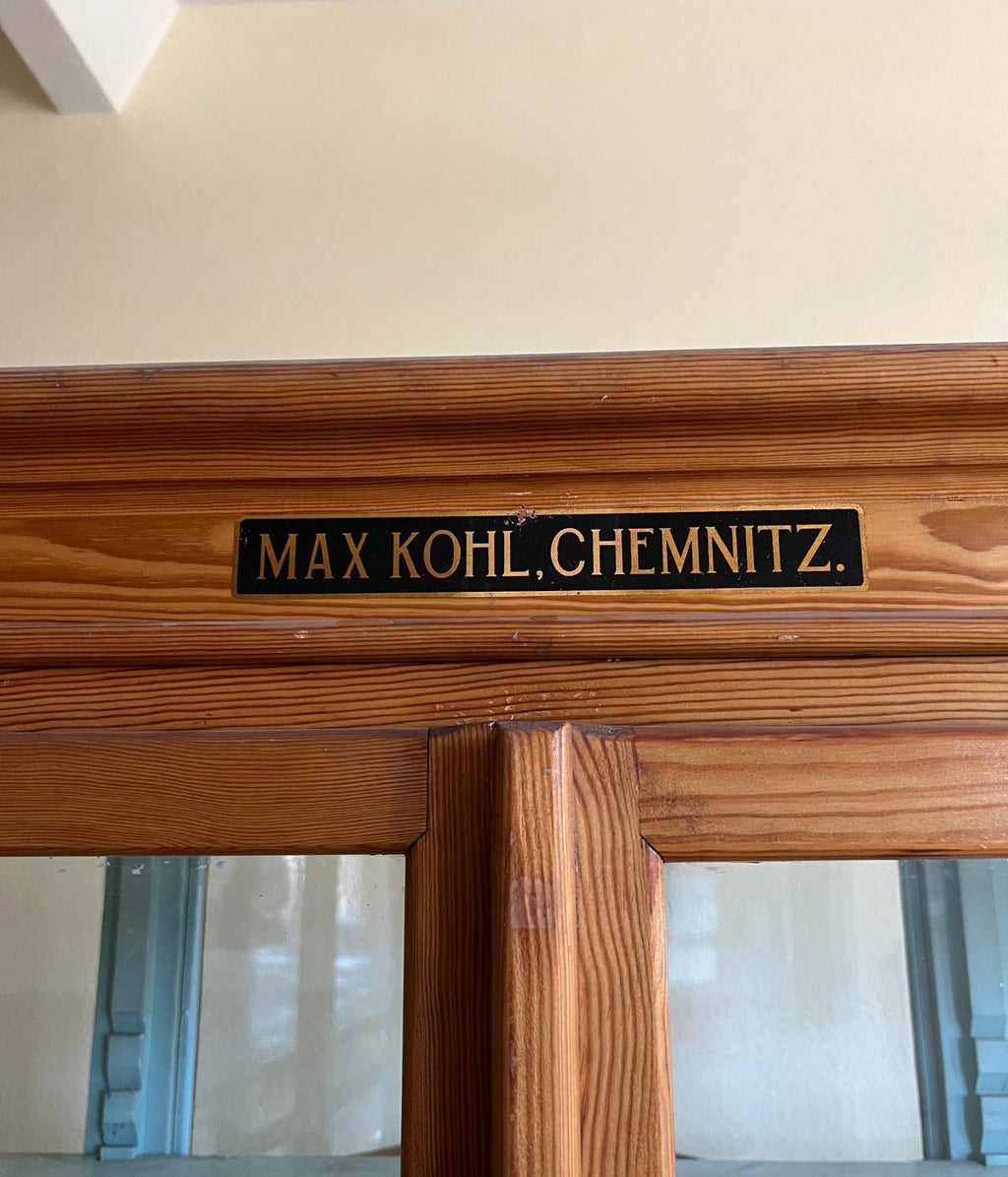 Detailaufnahme des originalen Herstellerschildes „Max Kohl Chemnitz“ am oberen Bereich des historischen Lehrmittelschranks. Das Schild dokumentiert die authentische Herkunft des Museumsmöbels.