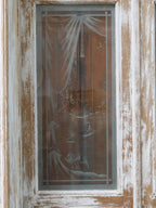 Nahaufnahme einer originalen satinierten Glasscheibe der historischen Tueranlage. Die dekorative Struktur des Jugendstilglases und die gealterte Holzrahmung sind deutlich zu erkennen.
