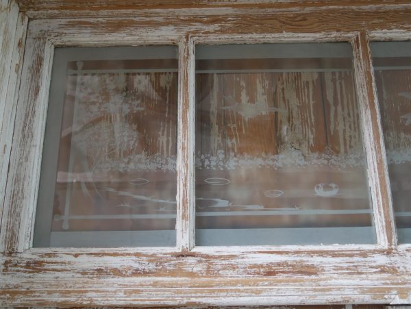 Nahaufnahme eines weiteren Bereichs des originalen Oberlichtfensters. Die historische Holzrahmung und die satinierten Glasscheiben befinden sich im authentischen Originalzustand.