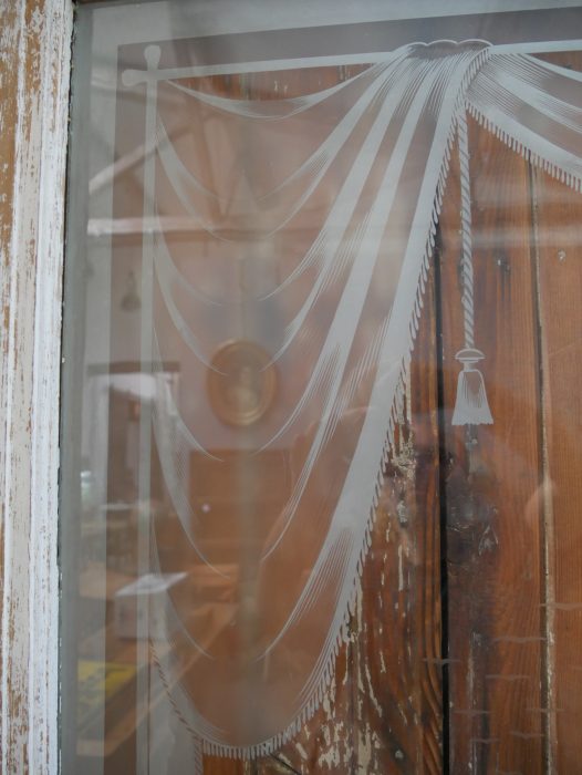 Nahaufnahme einer weiteren originalen satinierten Glasscheibe mit dekorativem Jugendstilmotiv. Die historische Verglasung sorgt für Sichtschutz und gleichzeitig für einen angenehmen Lichteinfall.