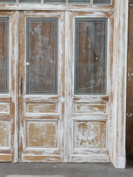 Schräg aufgenommene Frontansicht der antiken Tueranlage mit vier Türflügeln und Oberlicht. Die Perspektive verdeutlicht die Tiefe der Konstruktion sowie die originale Jugendstil-Ausführung.