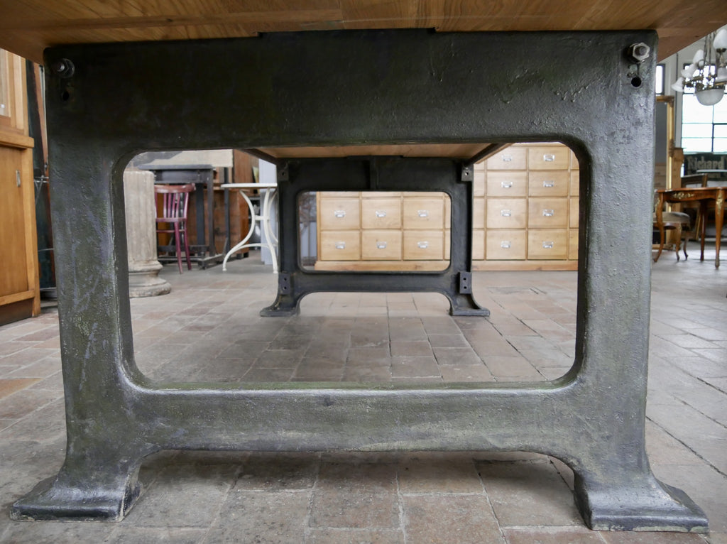 Blick unter den Tisch auf das massive Untergestell aus Gusseisen. Die schweren Maschinenfüße mit originaler grüner Lackierung und historischer Patina zeigen die stabile Konstruktion des originalen Tisches aus der Zeit um 1915–1920.
