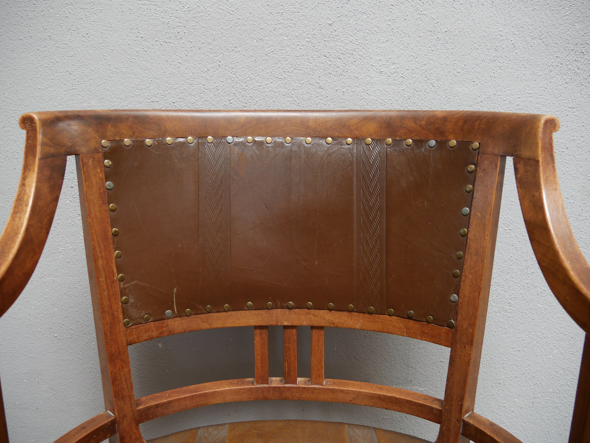 Detailansicht der Rückenlehne des Wiener Jugendstil-Armlehnstuhls mit originalem geprägtem Lederbezug. Das Leder zeigt dekorative Jugendstil-Motive und eine umlaufende Nagelverzierung. Die geschwungene Form der Rückenlehne und die feine Verarbeitung des historischen Nussbaumholzes sind deutlich sichtbar.