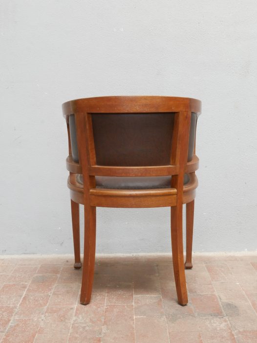 Rückansicht eines einzelnen Armlehnsessels. Die leicht gebogene Rückenlehne sowie die solide Konstruktion des massiven Eichenholzgestells werden deutlich sichtbar.