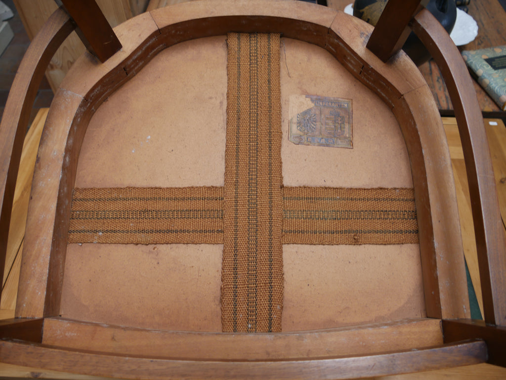 Detailaufnahme der Unterseite der Sitzfläche des historischen Jugendstil-Armlehnstuhls. Sichtbar sind die rückseitige Konstruktion der lederbezogenen Sitzfläche, die Holzrahmung und die handwerkliche Verarbeitung des antiken Stuhls. Die Aufnahme dokumentiert die originale Bauweise und den Erhaltungszustand des um 1905 gefertigten Möbelstücks.