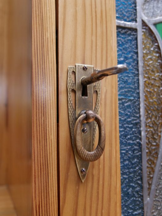 Detailaufnahme des originalen Türbeschlags mit Schlüsselschild und Griff. Der vollständig erhaltene Originalbeschlag ergänzt die hochwertige Ausstattung des seltenen Jugendstil-Vertikos.