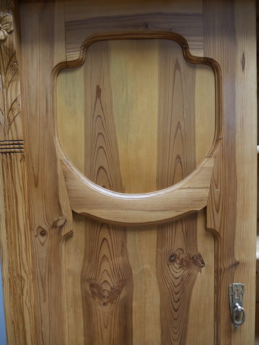 Detailaufnahme der charakteristischen geschnitzten Türfüllungen mit geschwungenen Jugendstil-Ornamenten. Die feinen Holzarbeiten sind typisch für hochwertige Möbel der Zeit um 1900.