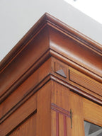 Detailaufnahme der profilierten Kranzleiste des originalen Jugendstil-Bibliotheksschranks. Das fein gearbeitete Gesims bildet einen eleganten oberen Abschluss des historischen Möbelstücks.