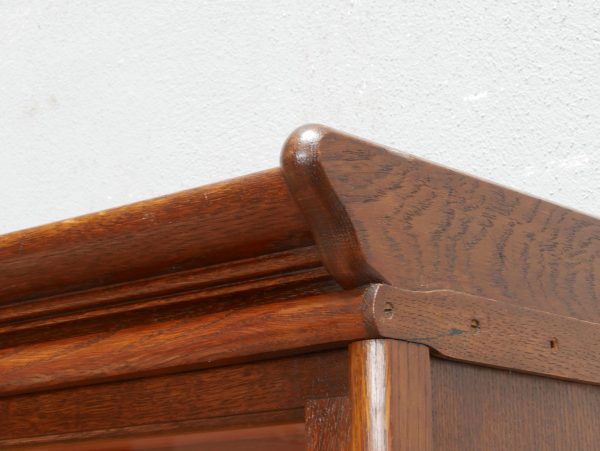 Detailaufnahme des profilierten Kranzgesimses des originalen Jugendstil-Bookcase-Bücherschranks. Das fein gearbeitete Profil und die geölte Eichenoberfläche unterstreichen die hochwertige Qualität des historischen Bibliotheksmöbels.
