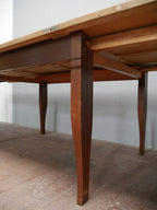Detailaufnahme der Unterseite des Jugendstil-Kulissentisches mit Blick auf die Tischzarge und die besondere mittig geteilte Fußkonstruktion. Beim Ausziehen trennen sich die beiden Fußhälften und stützen den verlängerten Esstisch, ohne dass zusätzliche ausklappbare Stützfüße benötigt werden.