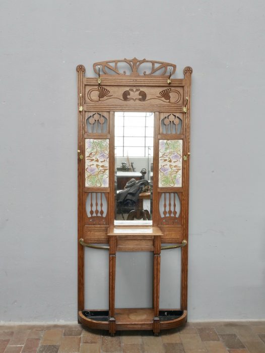 Frontalansicht der originalen Jugendstil-Garderobe um 1900. Die Aufnahme zeigt die harmonische Gestaltung mit Spiegel, Jugendstil-Ornamenten, originalen Fliesen, Ablagefach und sämtlichen Messinghaken.
