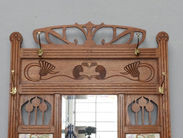 Detailaufnahme der reich geschnitzten Jugendstil-Krone mit Spiegelabschluss. Die elegante Ornamentik und die feine Holzschnitzerei unterstreichen die hochwertige handwerkliche Ausführung des Originalmöbels.