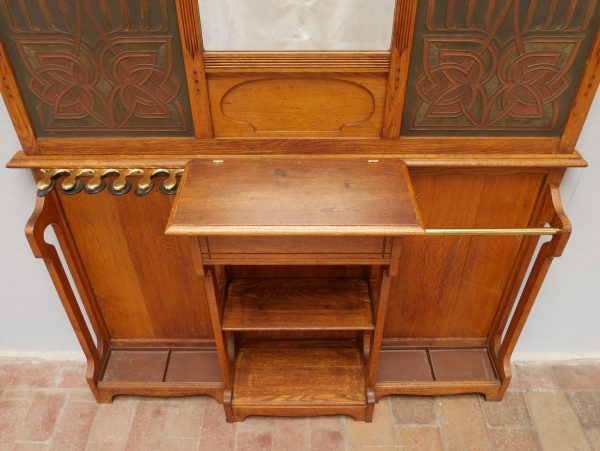 Detailaufnahme des mittleren Ablagebereichs mit kleinem Fach und oberer Ablage. Die funktionale Gestaltung bietet Platz für Handschuhe, Briefe oder Accessoires und ist harmonisch in das Jugendstil-Design integriert.
