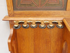 Detailaufnahme der dekorativen Zahnleiste unterhalb der Ablage. Die fein geschnitzten Holzelemente unterstreichen den hohen handwerklichen Anspruch und ergänzen die aufwendig gestalteten Lederfüllungen der Jugendstil-Garderobe.
