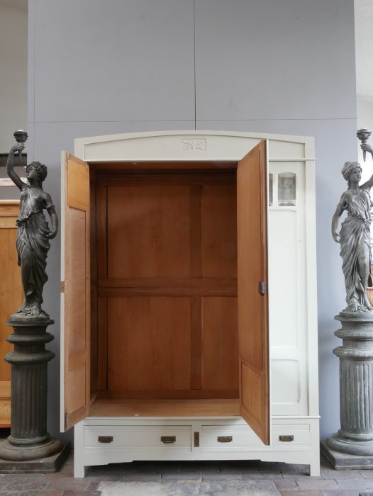 Vollständig geöffneter Jugendstil-Kleiderschrank mit freiem Blick auf den geräumigen Innenraum. Sichtbar sind die Kleiderstange, die hochwertige Holzausführung sowie die großzügige Stauraumaufteilung des restaurierten Originalmöbels aus Frankreich.
