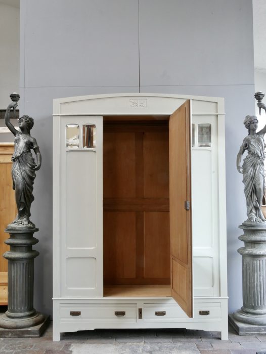 Jugendstil-Kleiderschrank mit geöffneter mittlerer Spiegeltür. Der großzügige Innenraum mit Kleiderstange ist sichtbar und zeigt die hochwertige restaurierte Innenausstattung des französischen Kleiderschranks um 1900.

