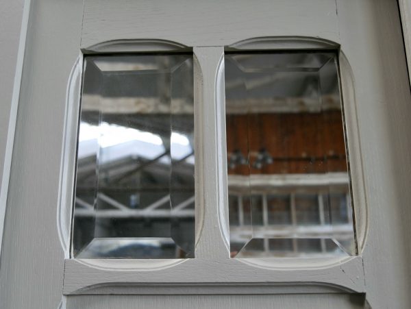Detailaufnahme des originalen Facettenspiegels in der mittleren Schranktür. Der hochwertige Spiegel mit geschliffenen Kanten gehört zur Originalausstattung des eleganten französischen Jugendstil-Kleiderschranks um 1900.
