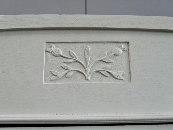 Detailaufnahme eines fein geschnitzten floralen Jugendstil-Ornaments in der Türfüllung des Kleiderschranks. Die sorgfältig ausgearbeitete Verzierung unterstreicht die hochwertige französische Handwerkskunst um 1900.
