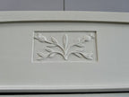 Detailaufnahme eines fein geschnitzten floralen Jugendstil-Ornaments in der Türfüllung des Kleiderschranks. Die sorgfältig ausgearbeitete Verzierung unterstreicht die hochwertige französische Handwerkskunst um 1900.

