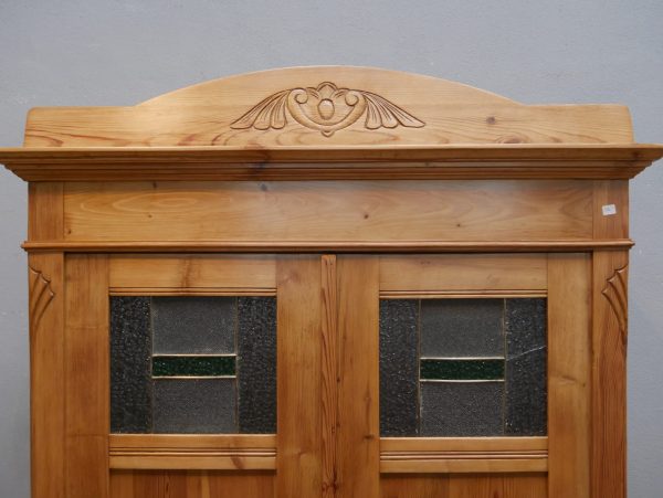 Detailaufnahme des oberen Türbereichs mit den originalen Bleiglasfenstern. Die historischen Bleiglasscheiben verleihen dem Jugendstil-Kleiderschrank seine besondere Ausstrahlung; eine Scheibe weist einen altersbedingten Riss auf.
