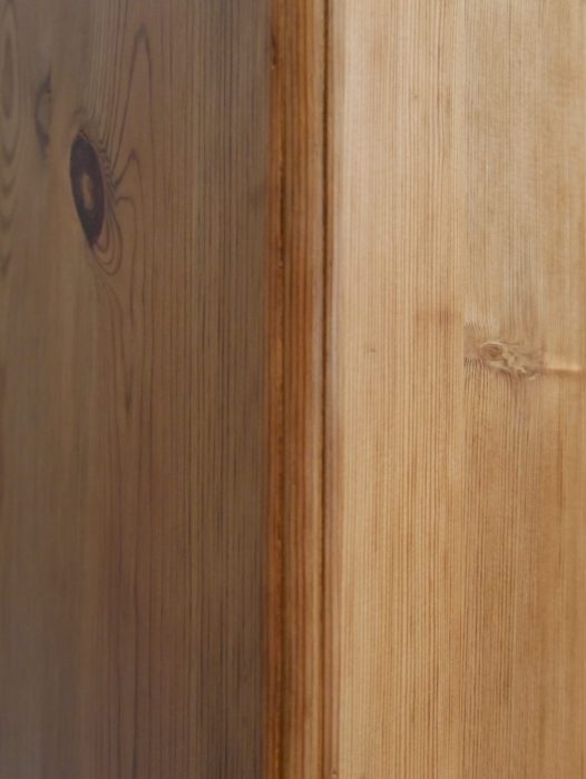 Detailaufnahme der gewachsten Weichholzoberfläche mit natürlicher Holzmaserung und wohnfertig restaurierter Oberfläche. Die Aufnahme zeigt den authentischen Charakter des historischen Jugendstil-Schranks.