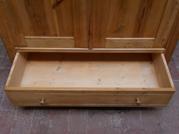 Detailaufnahme des geöffneten Schubkastens im unteren Bereich des Schranks. Die Aufnahme zeigt die massive Holzkonstruktion und die hochwertige Verarbeitung des historischen Möbelstücks.