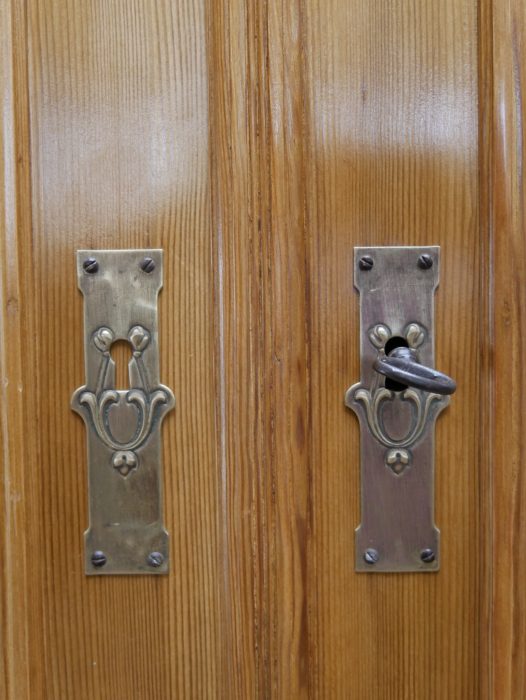 Nahaufnahme der originalen Türbeschläge des Jugendstil-Küchenbuffetts. Die historischen Metallbeschläge unterstreichen den authentischen Charakter des restaurierten Möbelstücks.