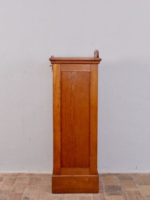 Linke Seitenansicht des originalen Rollschranks. Die schlichte Jugendstilgestaltung, die schöne Holzmaserung und der gepflegte unrestaurierte Originalzustand sind deutlich erkennbar.