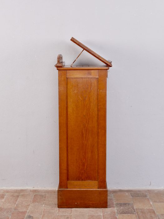Seitenansicht des Rollschranks mit aufgeklappter und in der Neigung verstellbarer Schreibplatte. Die Aufnahme zeigt die elegante Seitenansicht und die praktische Stehpultfunktion.
