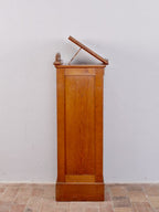 Seitenansicht des Rollschranks mit aufgeklappter und in der Neigung verstellbarer Schreibplatte. Die Aufnahme zeigt die elegante Seitenansicht und die praktische Stehpultfunktion.
