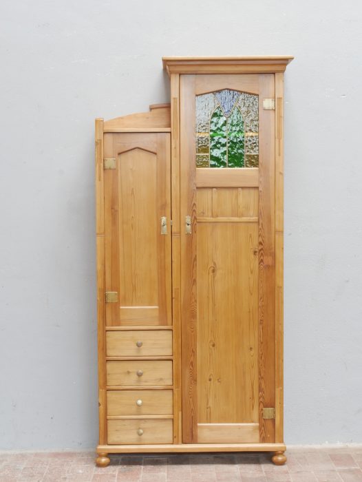 Frontalansicht des historischen Jugendstil-Schranks mit geschlossenen Türen. Besonders auffällig sind die asymmetrische Gestaltung, das originale Bleiglasfenster sowie die hochwertige handwerkliche Verarbeitung der Einzelanfertigung.