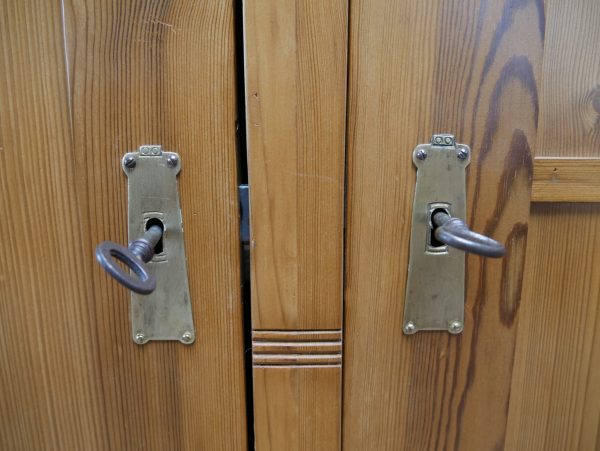 Nahaufnahme der originalen historischen Türbeschläge mit schöner Alters-Patina. Die authentischen Metallbeschläge unterstreichen den hochwertigen Originalzustand des Schranks.