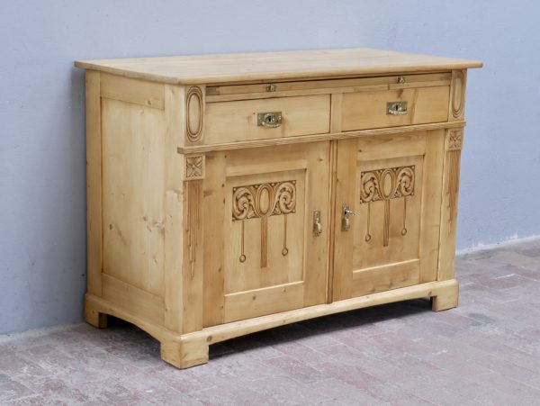 Schräg aufgenommene Seitenansicht der restaurierten Jugendstil-Anrichte aus Weichholz. Die Aufnahme zeigt die massive Bauweise, die seitlichen Füllungen und die harmonischen Proportionen des historischen Möbels.