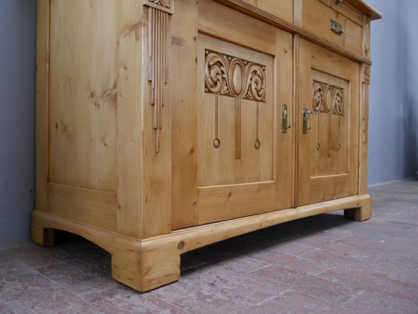Schräg aufgenommene Seitenansicht des historischen Sideboards. Sichtbar sind die seitlichen Füllungen, der stabile Sockel und die hochwertige Verarbeitung der restaurierten Jugendstil-Anrichte.