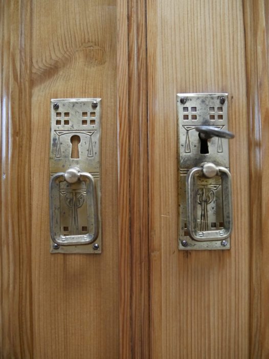 Detailaufnahme der originalen Türbeschläge mit Schloss und Griffen. Die historischen Metallbeschläge sind vollständig erhalten und harmonieren mit der restaurierten Weichholzoberfläche.