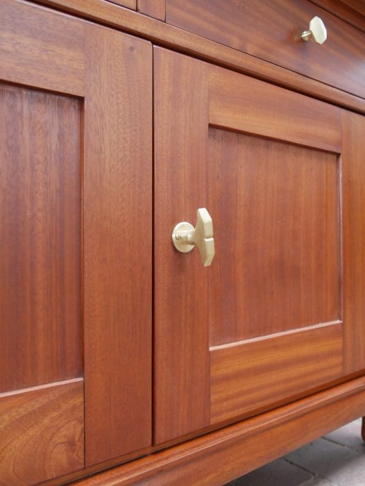 Detailaufnahme der unteren Türen mit originalen Beschlägen und fein gemaserter Mahagonioberfläche. Die klare Linienführung steht exemplarisch für den frühen Jugendstil.