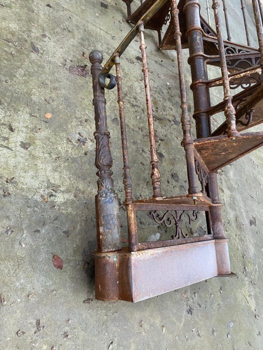 Detailaufnahme des unteren Treppenantritts der historischen Jugendstil-Wendeltreppe. Sichtbar sind der erste Treppenlauf, die Mittelsäule sowie die massive Konstruktion aus Gusseisen und Schmiedeeisen.