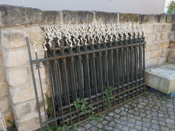 Detailansicht eines originalen Zaunfeldes der Jugendstil-Zaunanlage um 1890. Das historische Schmiedeeisen-Zaunfeld zeigt die charakteristischen senkrechten Stäbe, dekorativen Spitzen und die geschwungene obere Linie. Die originale Patina und die hochwertige Schmiedearbeit sind sehr gut erhalten.