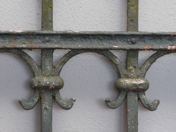 Detailaufnahme eines geschmiedeten Verbindungselements im unteren Bereich der Zaunanlage. Sichtbar sind die massiven Schmiedearbeiten und die originale handwerkliche Konstruktion des historischen Zauns.
