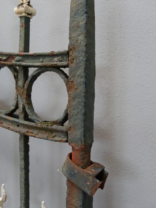 Detailaufnahme eines seitlichen Torpfostens mit angeschlossenem Zaunfeld. Die Verbindung zwischen Pfosten und Zaunelement verdeutlicht die massive Schmiedeeisenkonstruktion der historischen Zaunanlage.