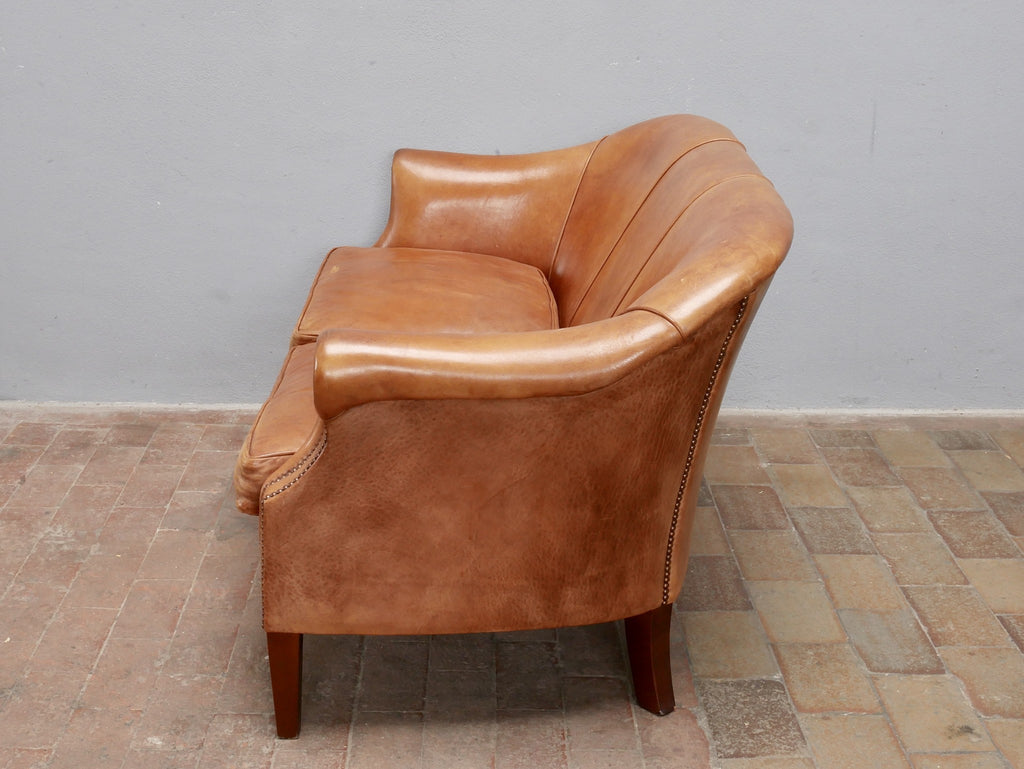 Rechte Seitenansicht des Vintage-Ledersofas aus den Niederlanden um 1970. Die elegante Linienführung, die geschwungene Rückenlehne sowie die charakteristische Patina des Schafsleders werden aus dieser Perspektive besonders deutlich.
