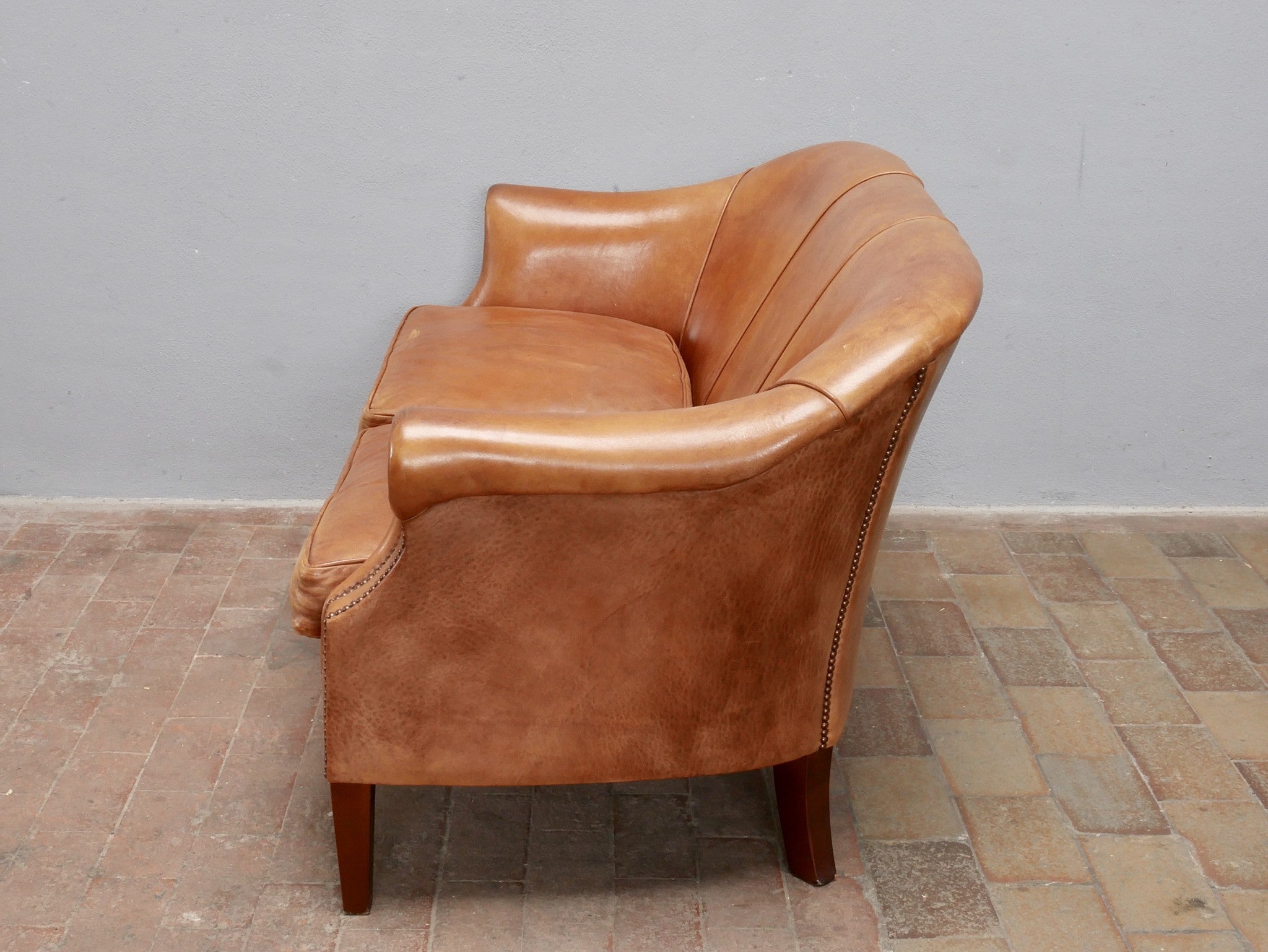 Rechte Seitenansicht des Vintage-Ledersofas aus den Niederlanden um 1970. Die elegante Linienführung, die geschwungene Rückenlehne sowie die charakteristische Patina des Schafsleders werden aus dieser Perspektive besonders deutlich.
