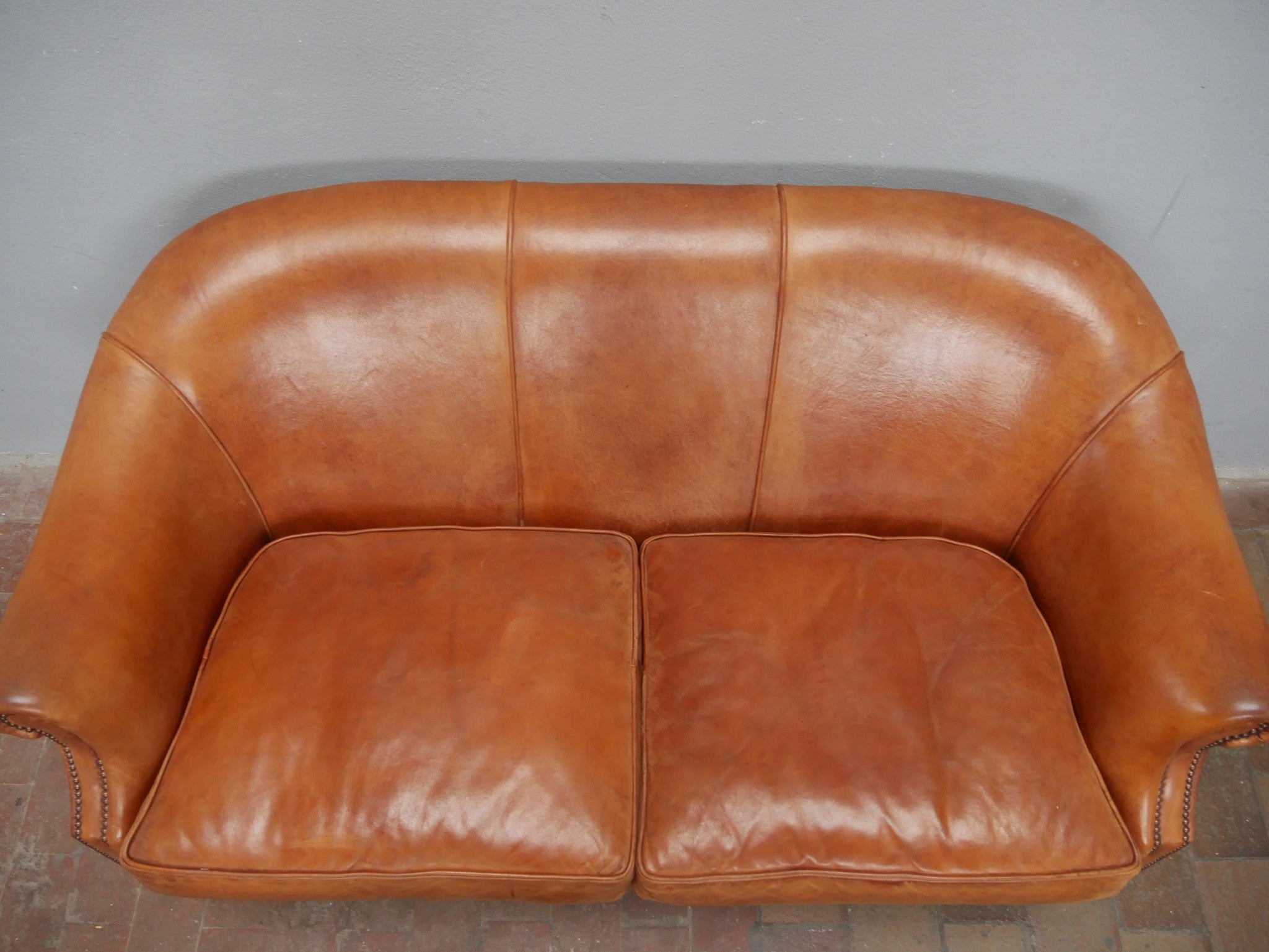 Detailaufnahme der oberen Rückenlehne und der beiden Sitzpolster des niederländischen Lounge-Sofas. Sichtbar sind die natürliche Lederstruktur, die hochwertige Verarbeitung und die schöne, gleichmäßig gewachsene Patina des Schafsleders.
