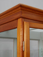 Detailaufnahme eines Eckpfostens mit originalem Holzrahmen und Verglasung. Die Aufnahme zeigt die präzise Verarbeitung und den authentischen Erhaltungszustand des historischen Schranks.